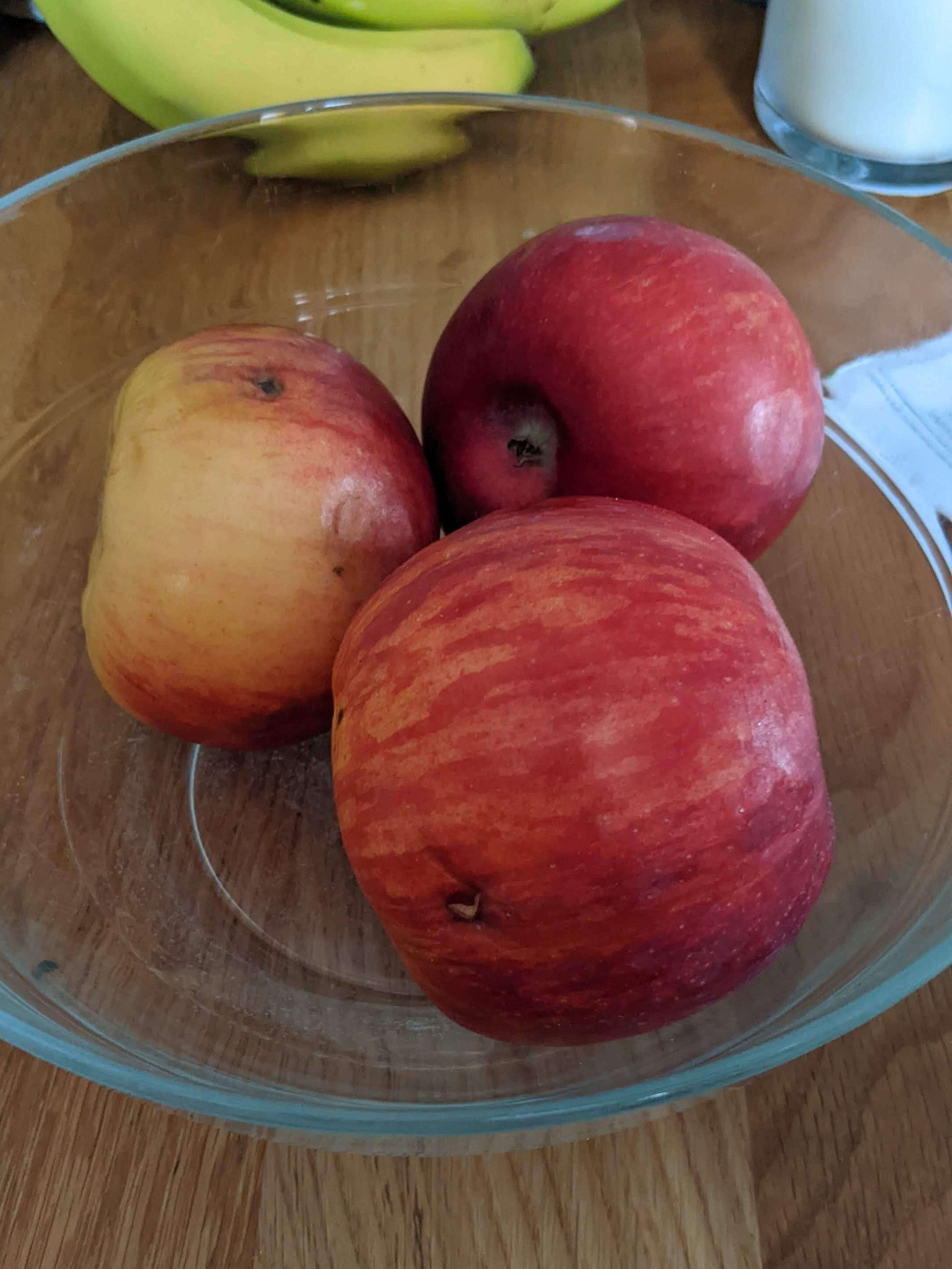 three apples in a glass bowl
