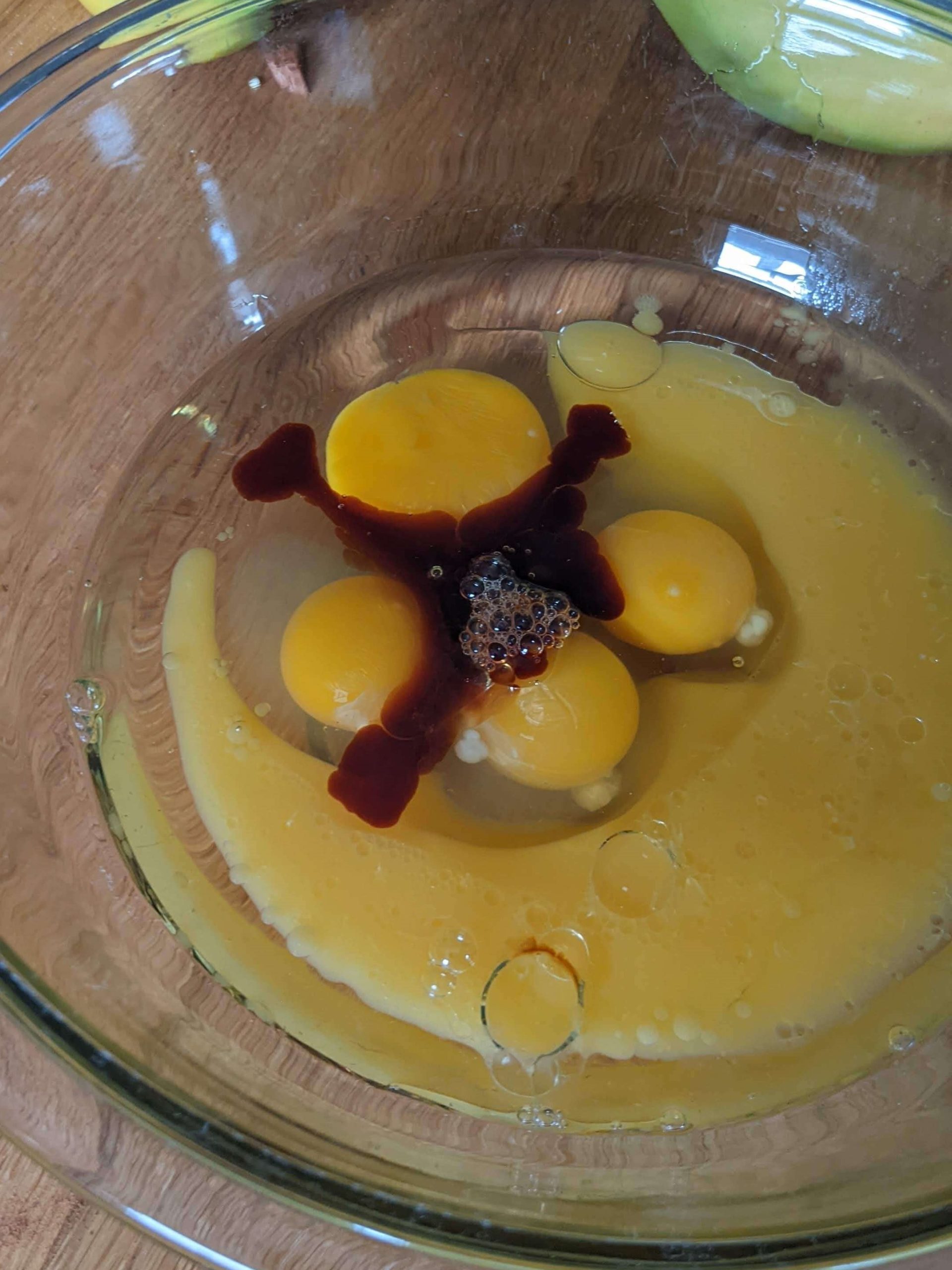 4 eggs and vanilla in a bowl with orange liquid