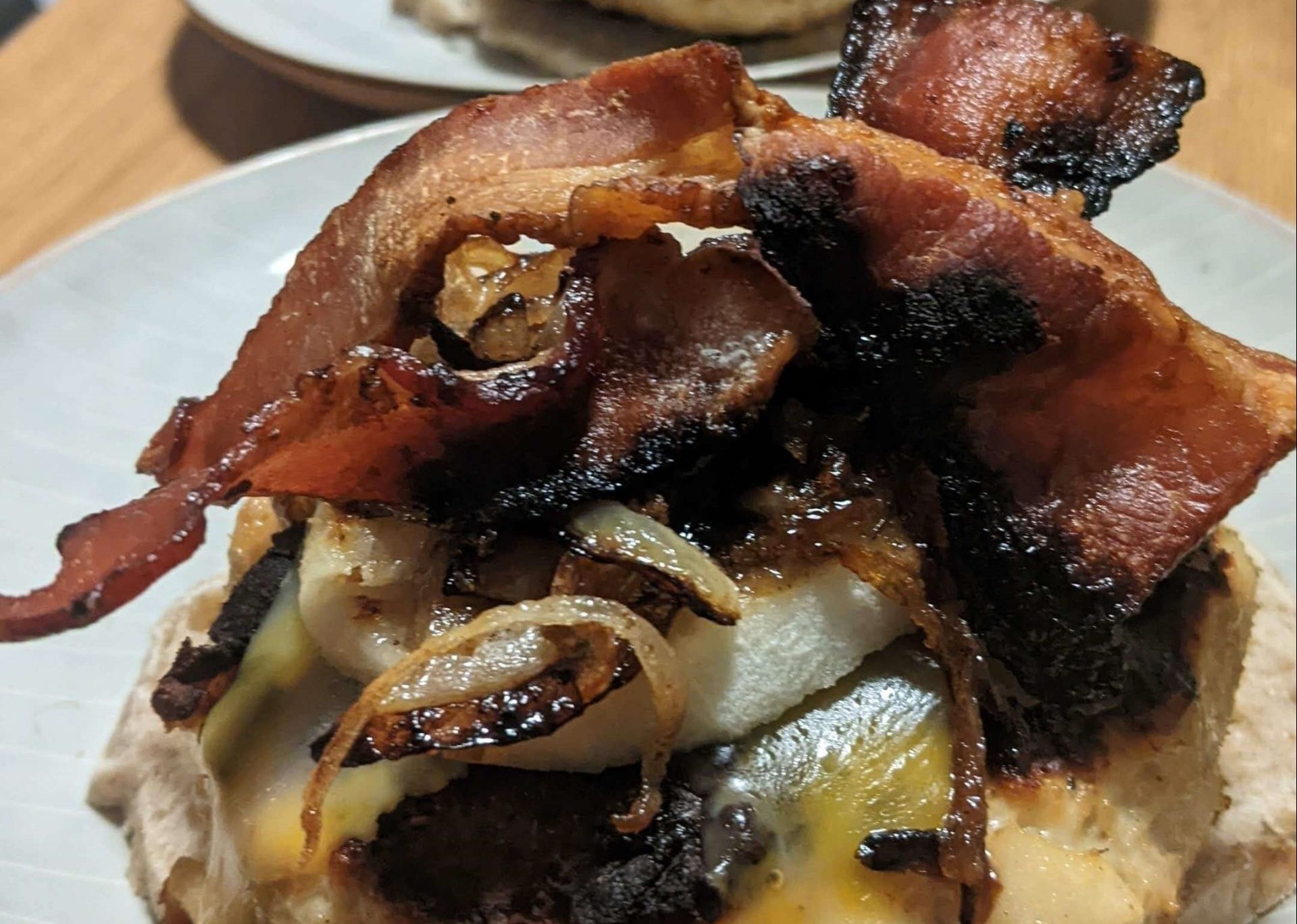 chicken burgers on a slice of bread topped with cooked onions and bacon on a plate 