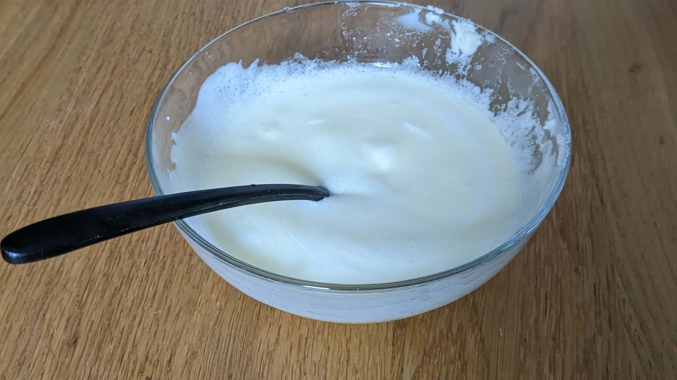 melted butter in a glass bowl with a black utensil on a wooden counter