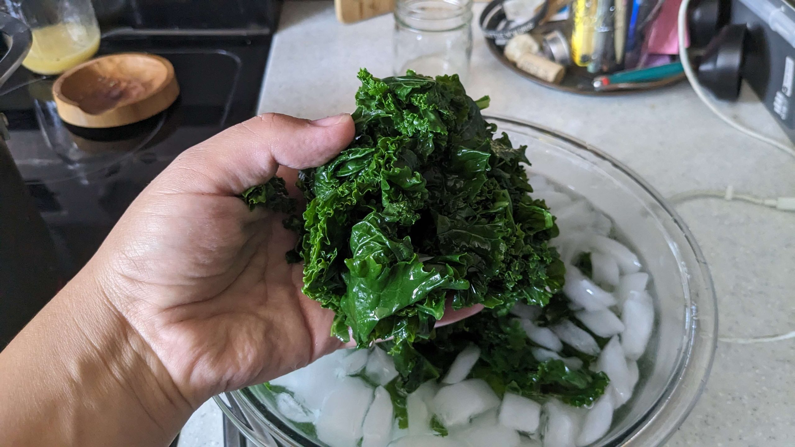woman squeezing kale over a bowl of ice