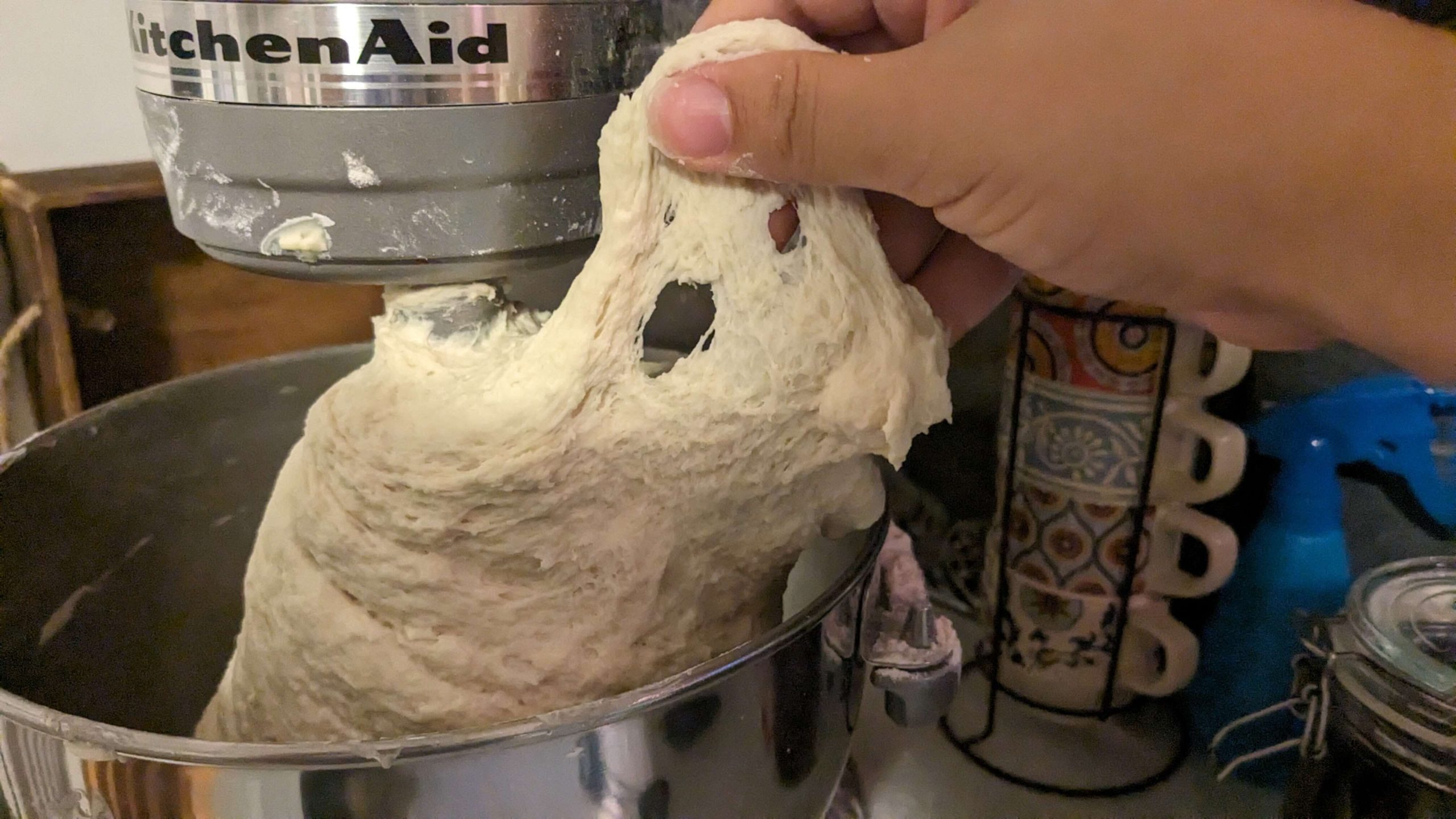 woman pulling dough out of a kitchen aid mixer