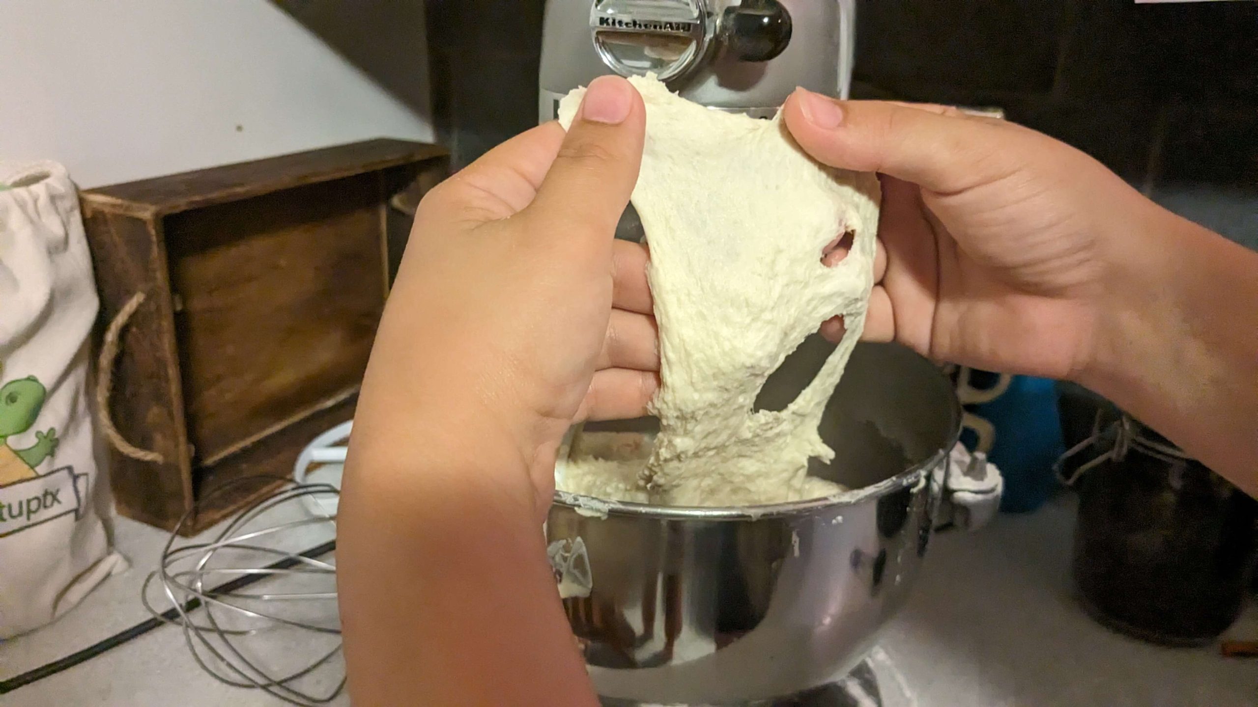 woman stretching dough out of a kitchen aid mixer