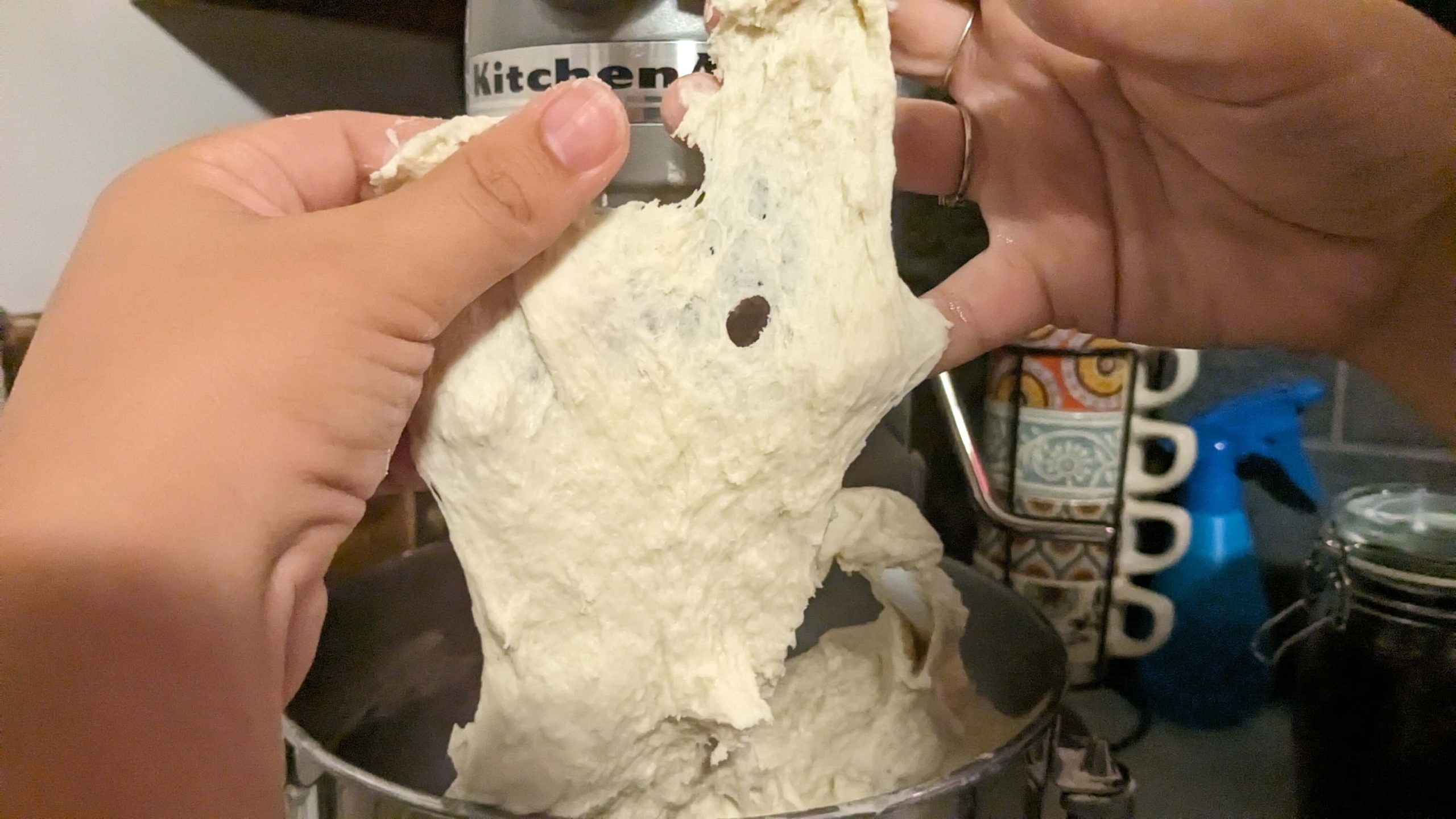 woman stretching dough that rips in front of a kitchen aid mixer