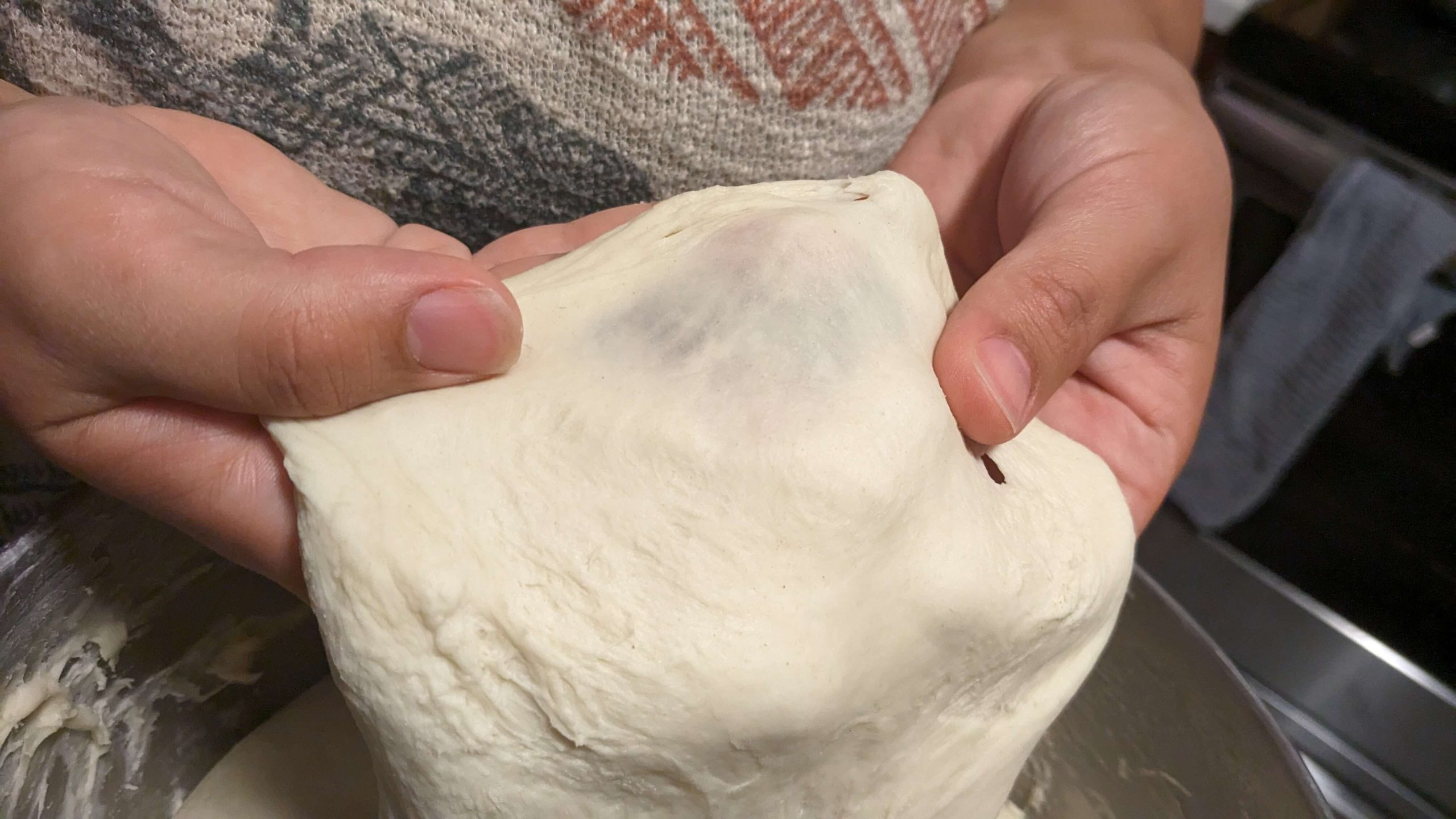 dough that is transparent as it is stretched by a woman