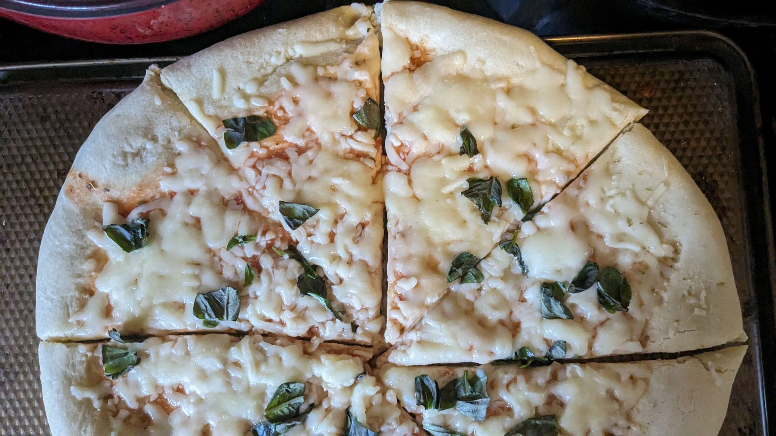 sliced cooked cheese pizza with torn basil on top