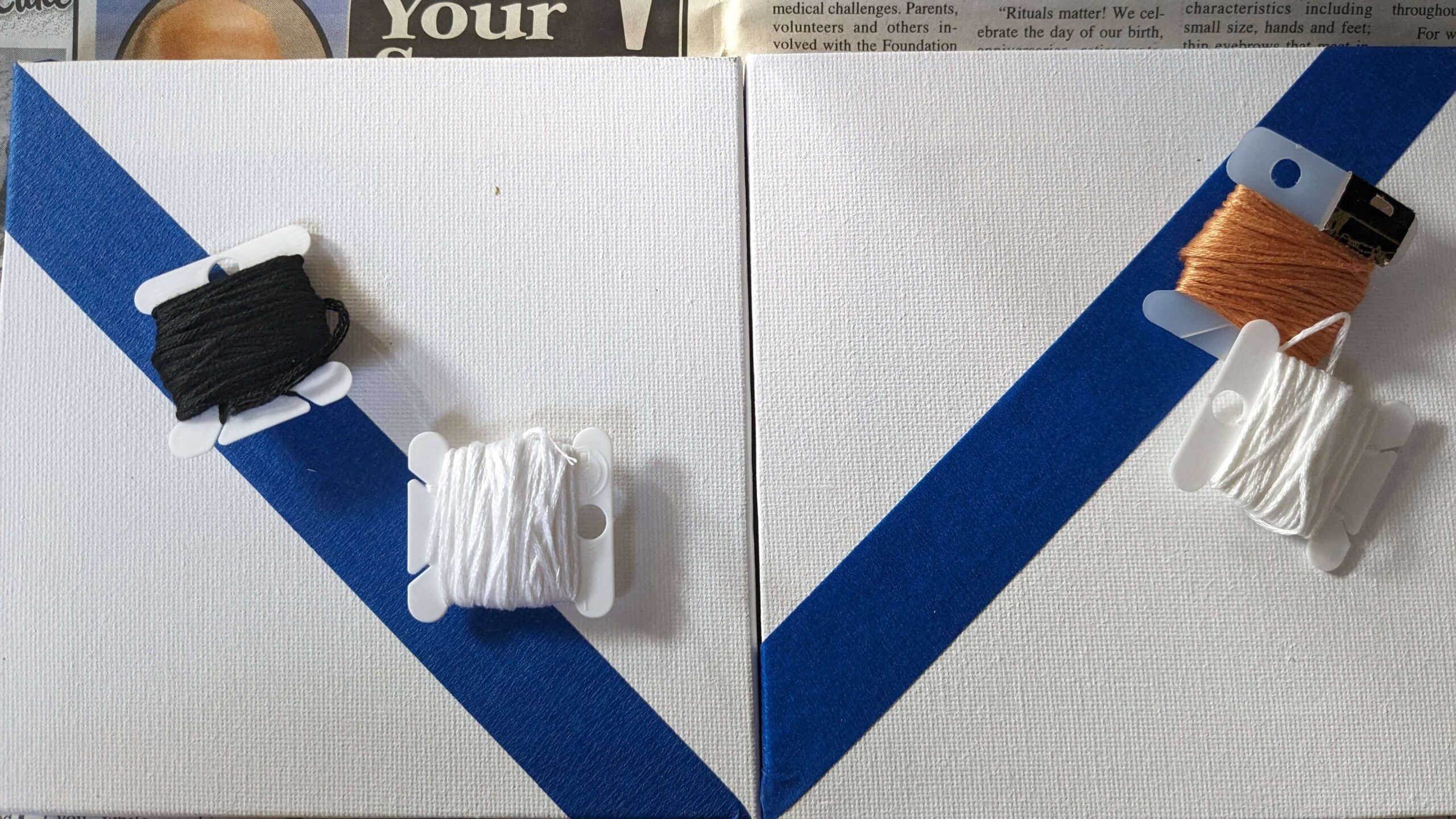 two square canvases with blue painters tape diagonally and embroidery floss