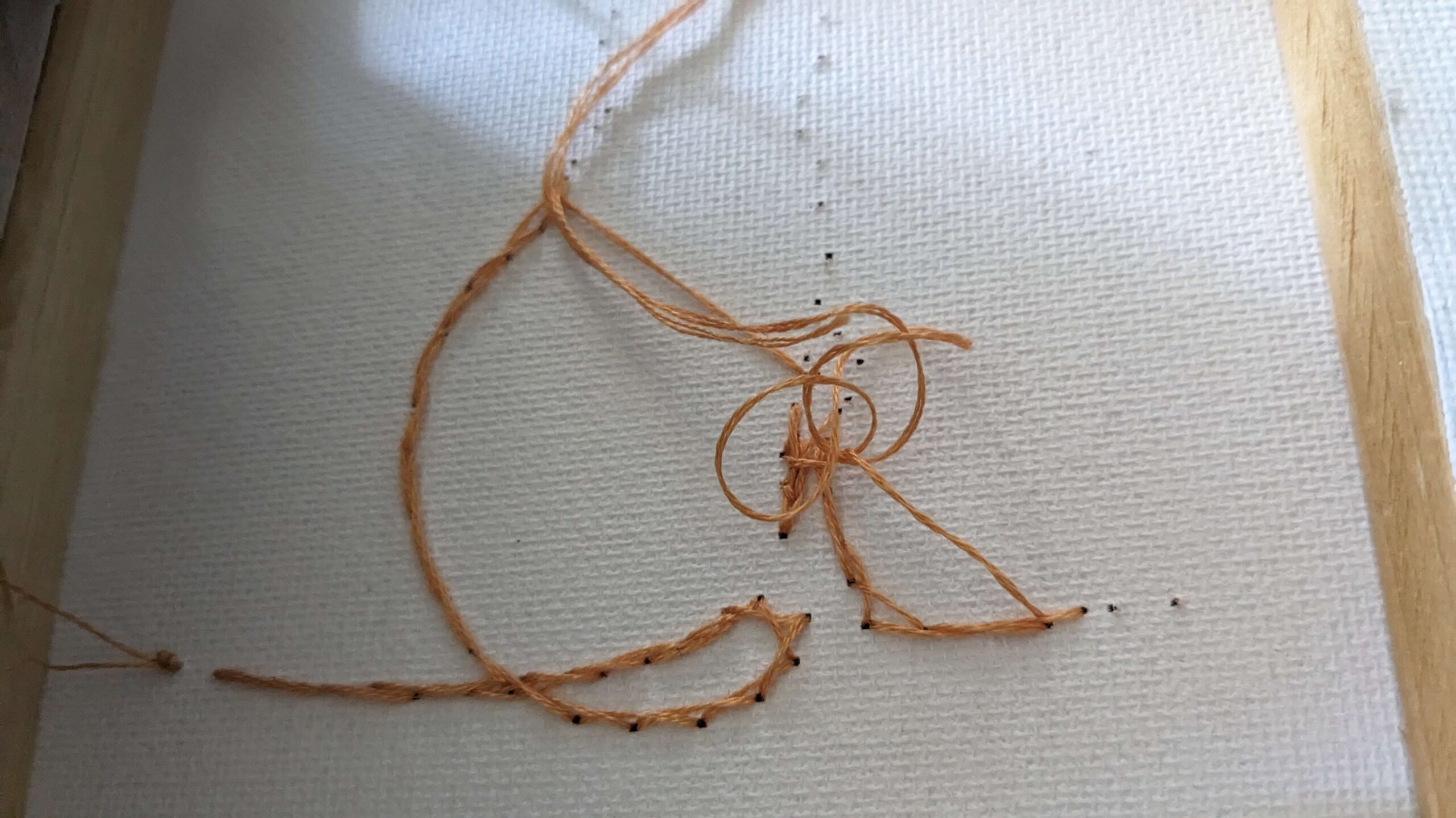 back of a canvas with orange embroidery floss in the shape of a cat