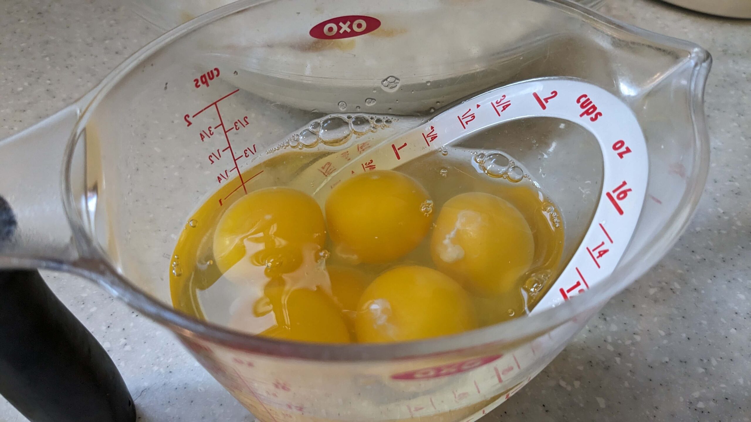 raw egg yokes in their whites in a measuring cup