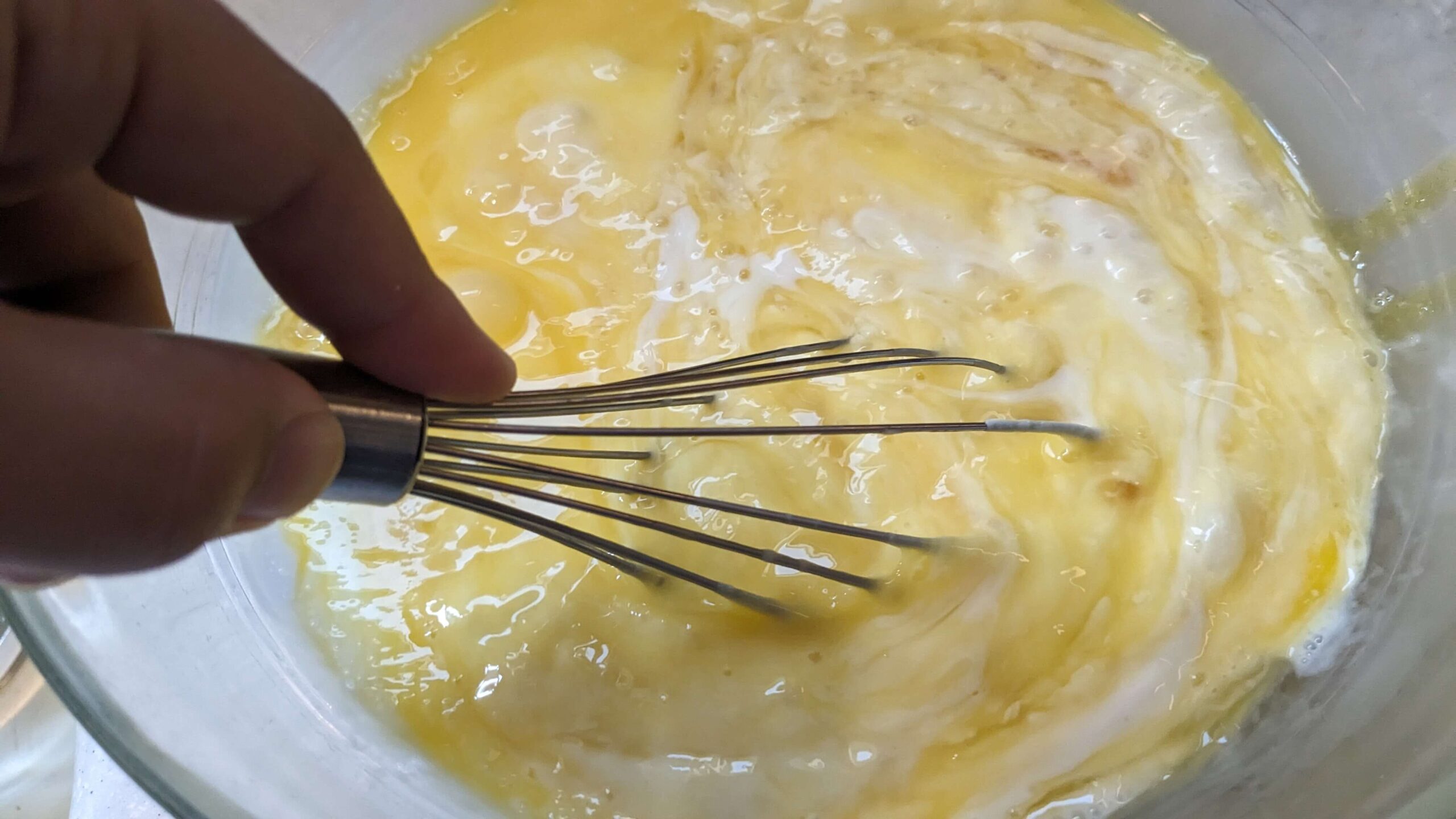 woman whisking raw eggs and sourdough discard