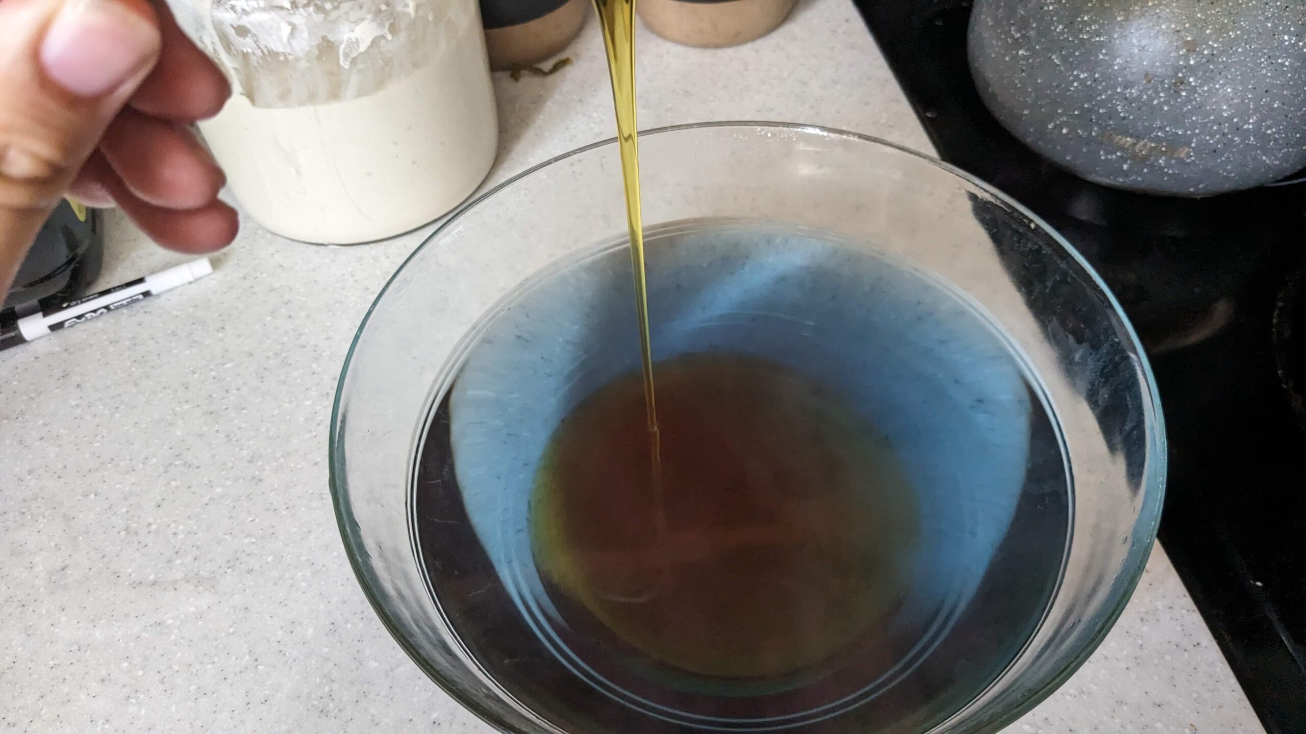 honey pouring into a bowl of blue liquid that is turning amber