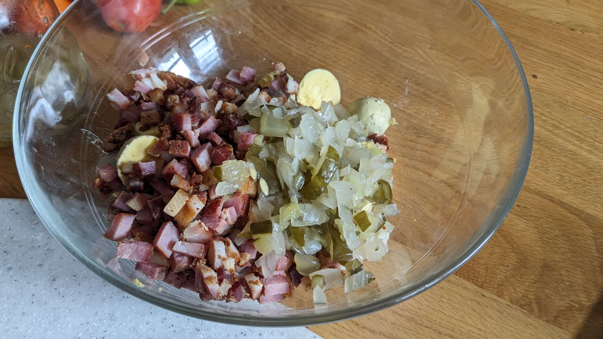 chopped bacon and hard boiled egg yolks with chopped pickled onions and pickles in a glass bowl