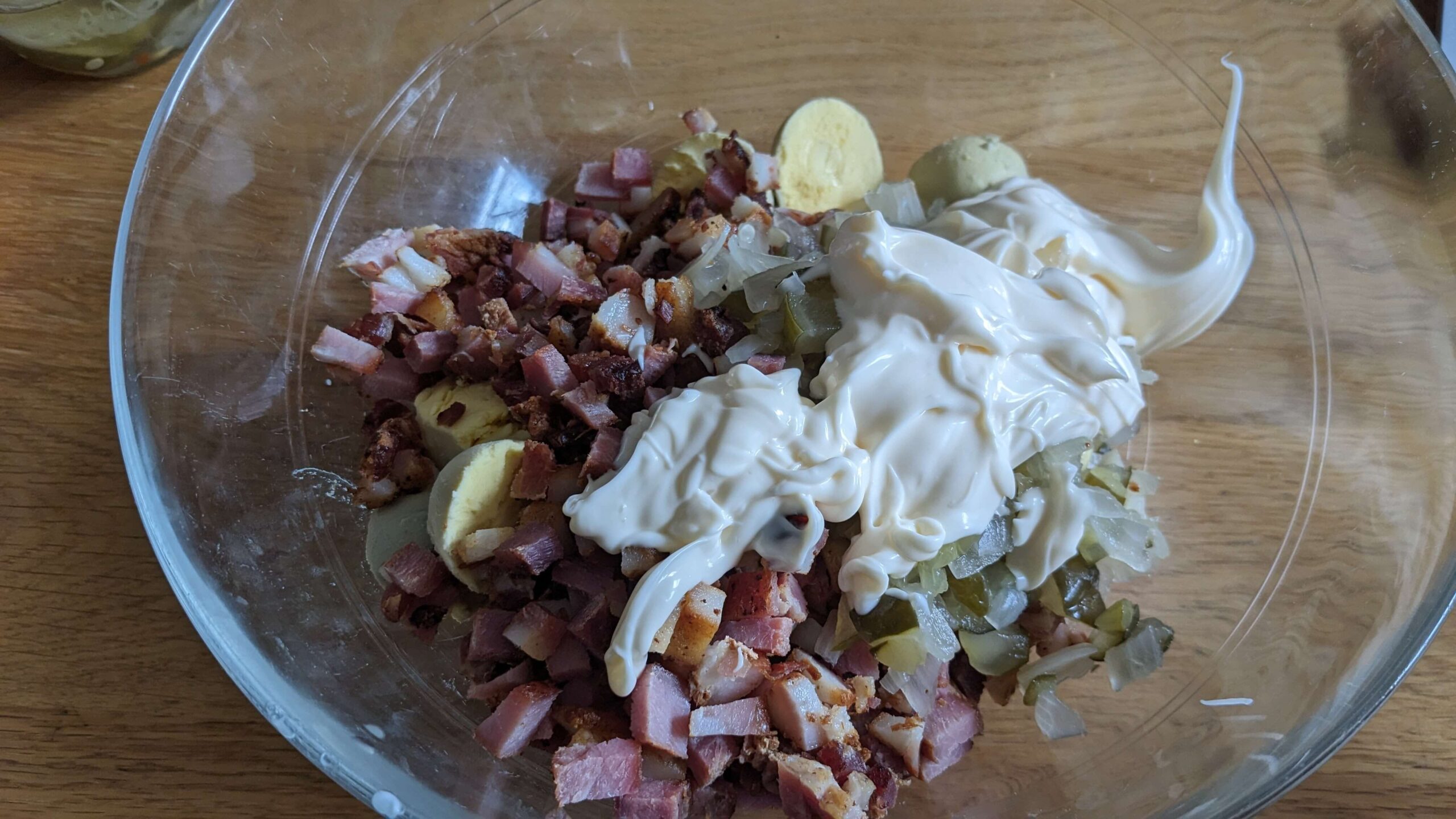 chopped bacon and hard boiled egg yolks and pickles with mayo in a glass bowl