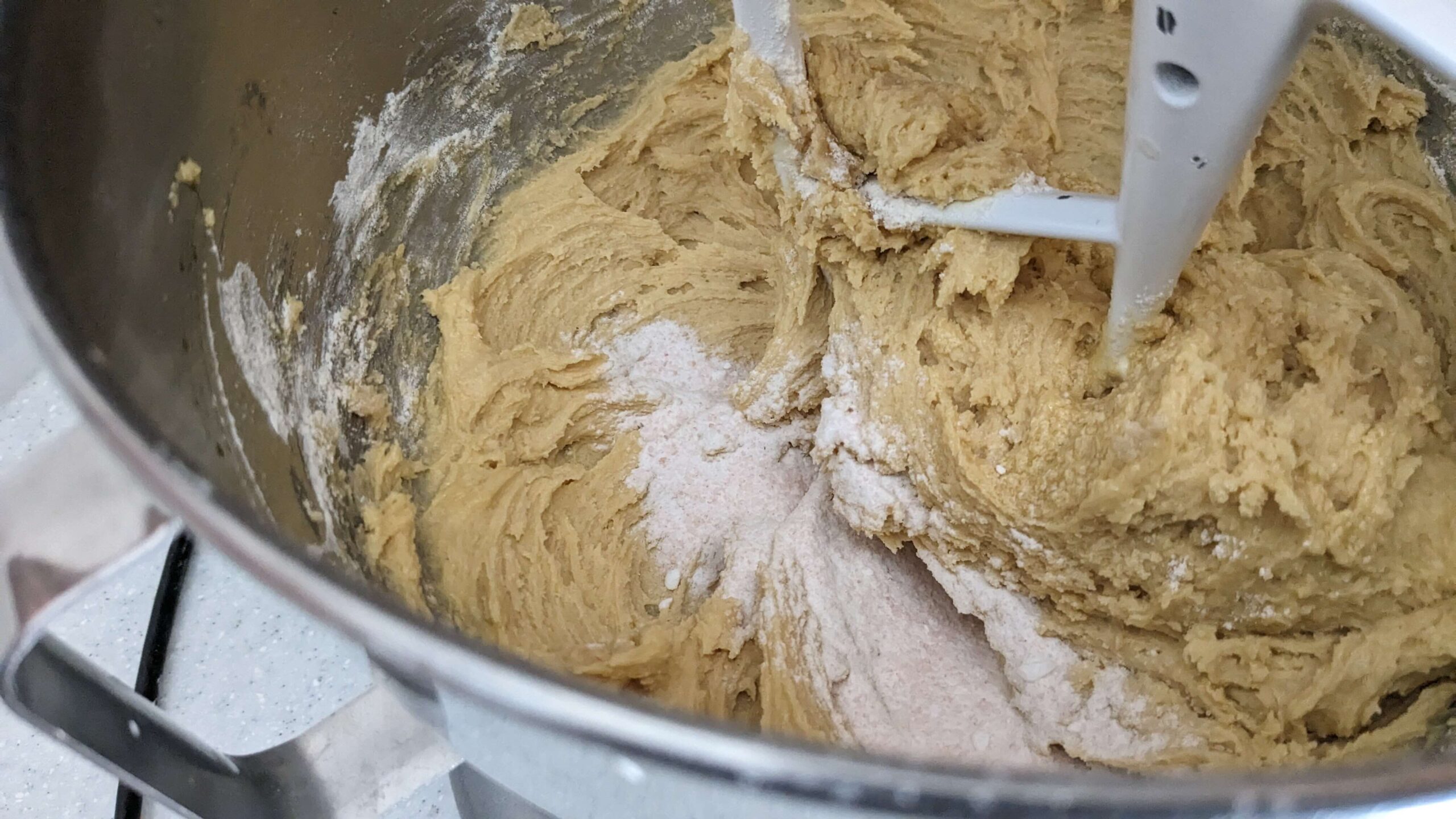 close up of a kitchen aid mixer mixing flour into cookie dough