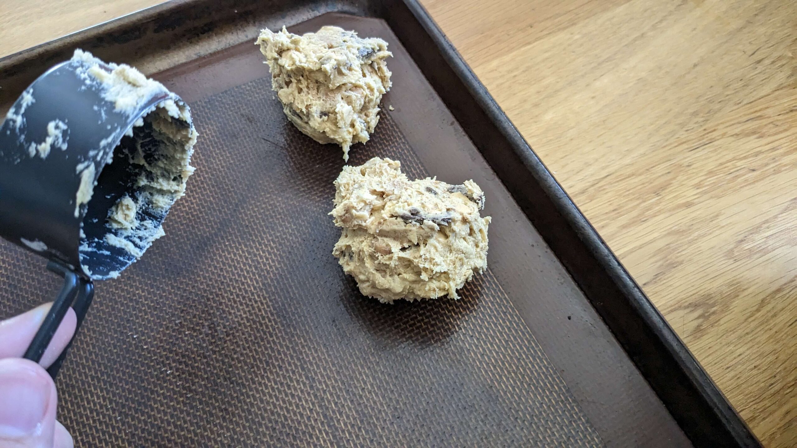 two scoops of cookie dough on a silpat on a baking tray