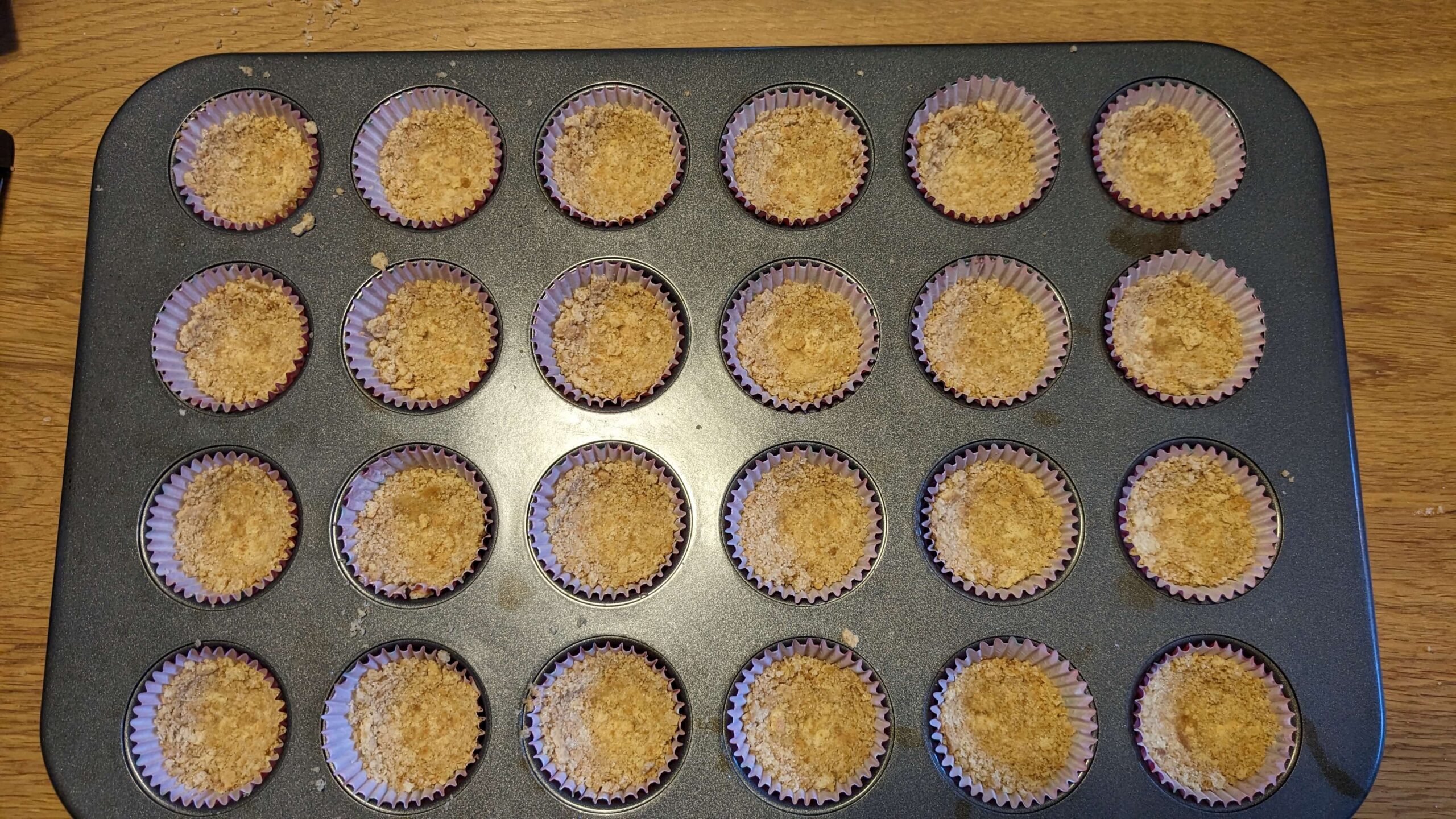 raw graham cracker crust in a tray of mini muffins