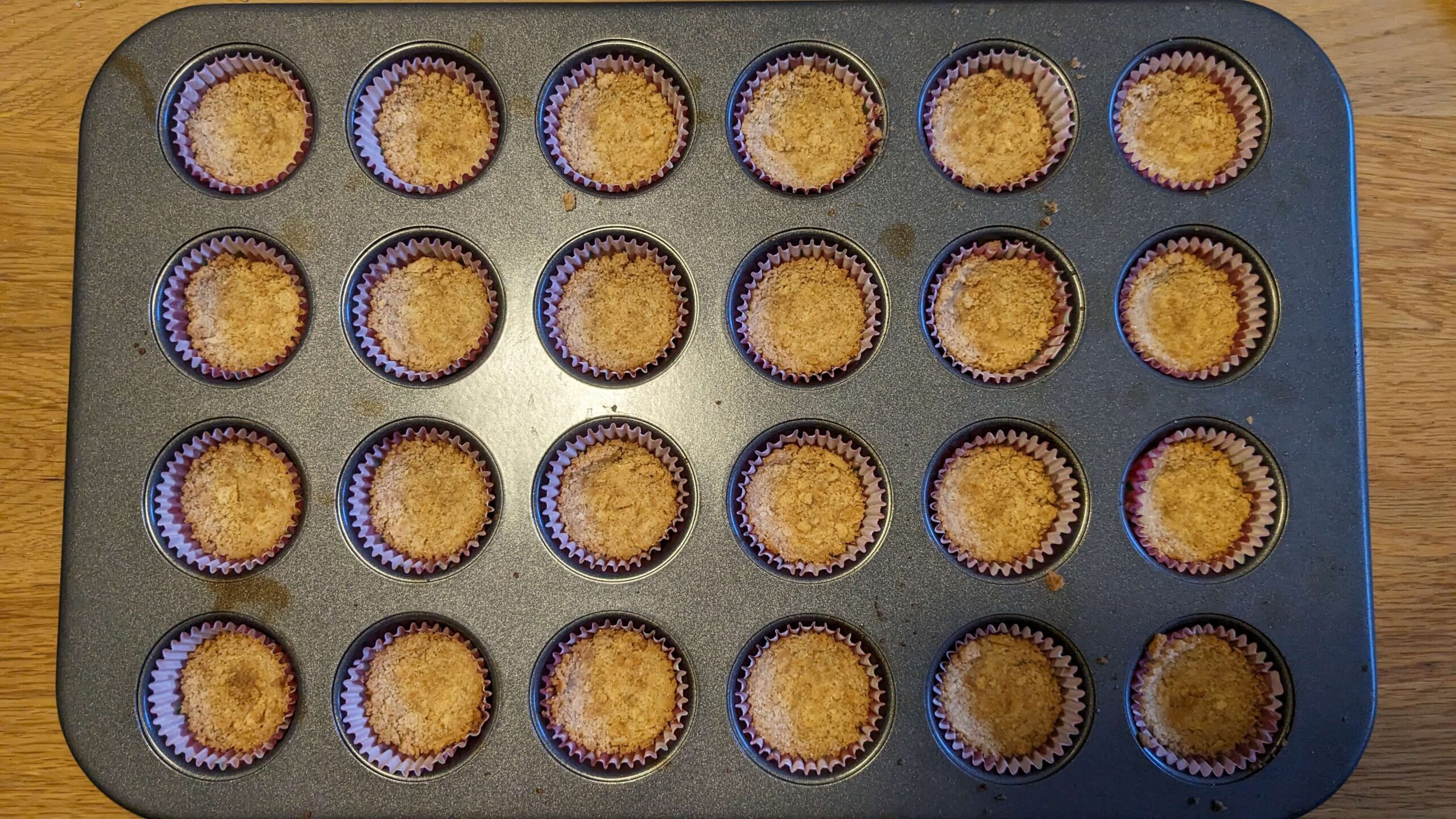 cooked graham cracker crust in a tray of mini muffins