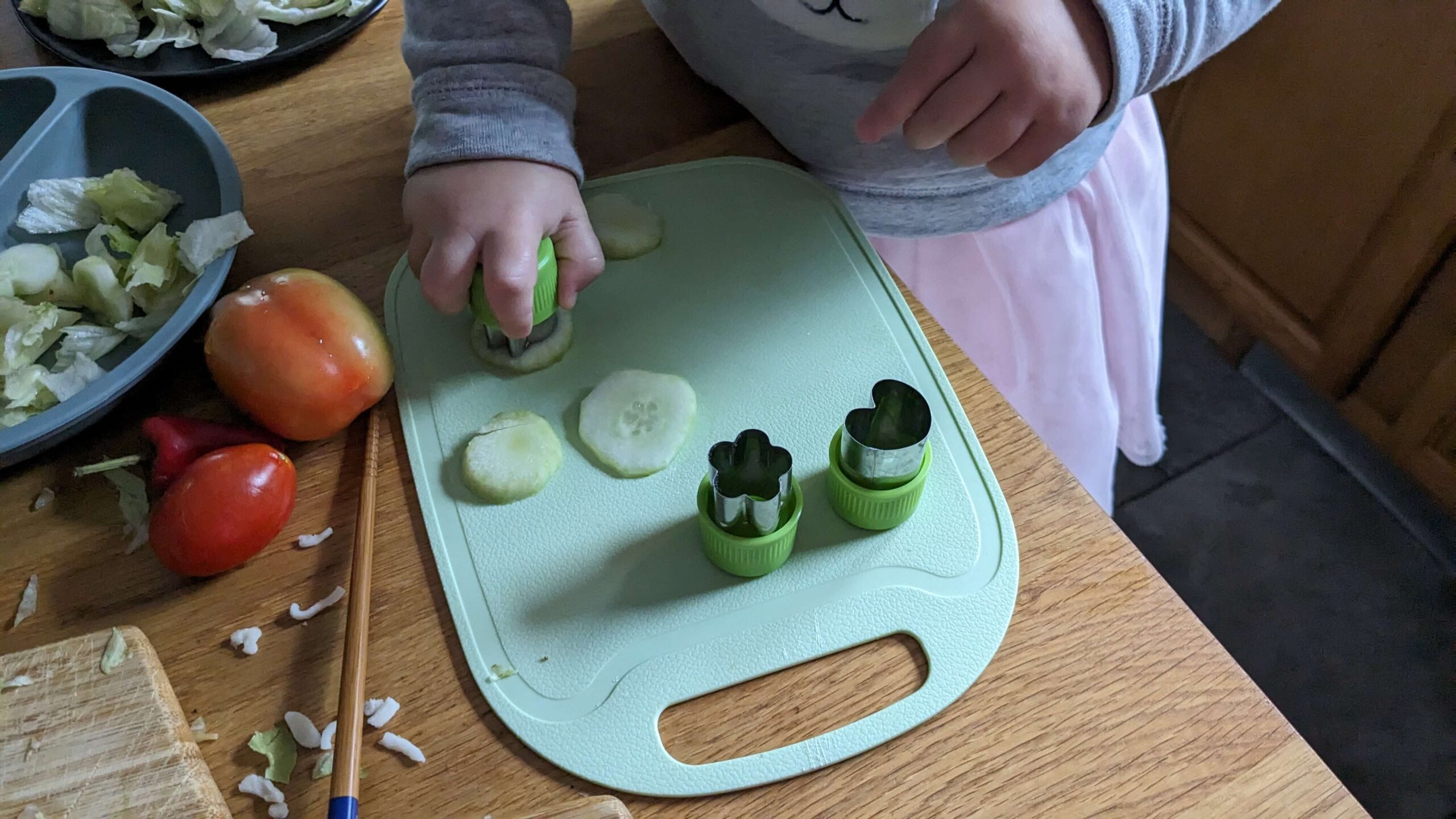 toddler girl punching cut outs of slices of cucumbers