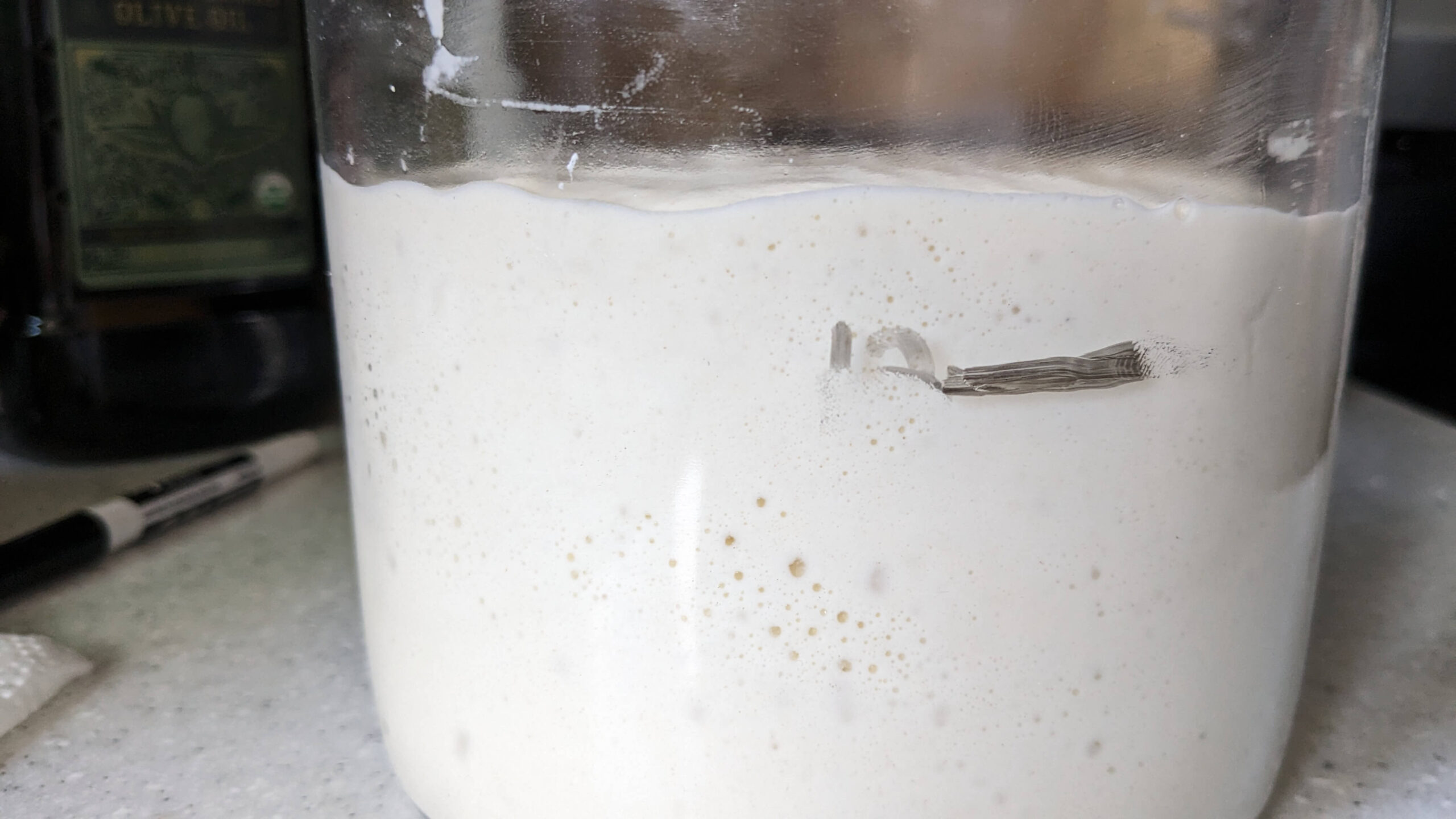 jar of rising sourdough starter on a stove top
