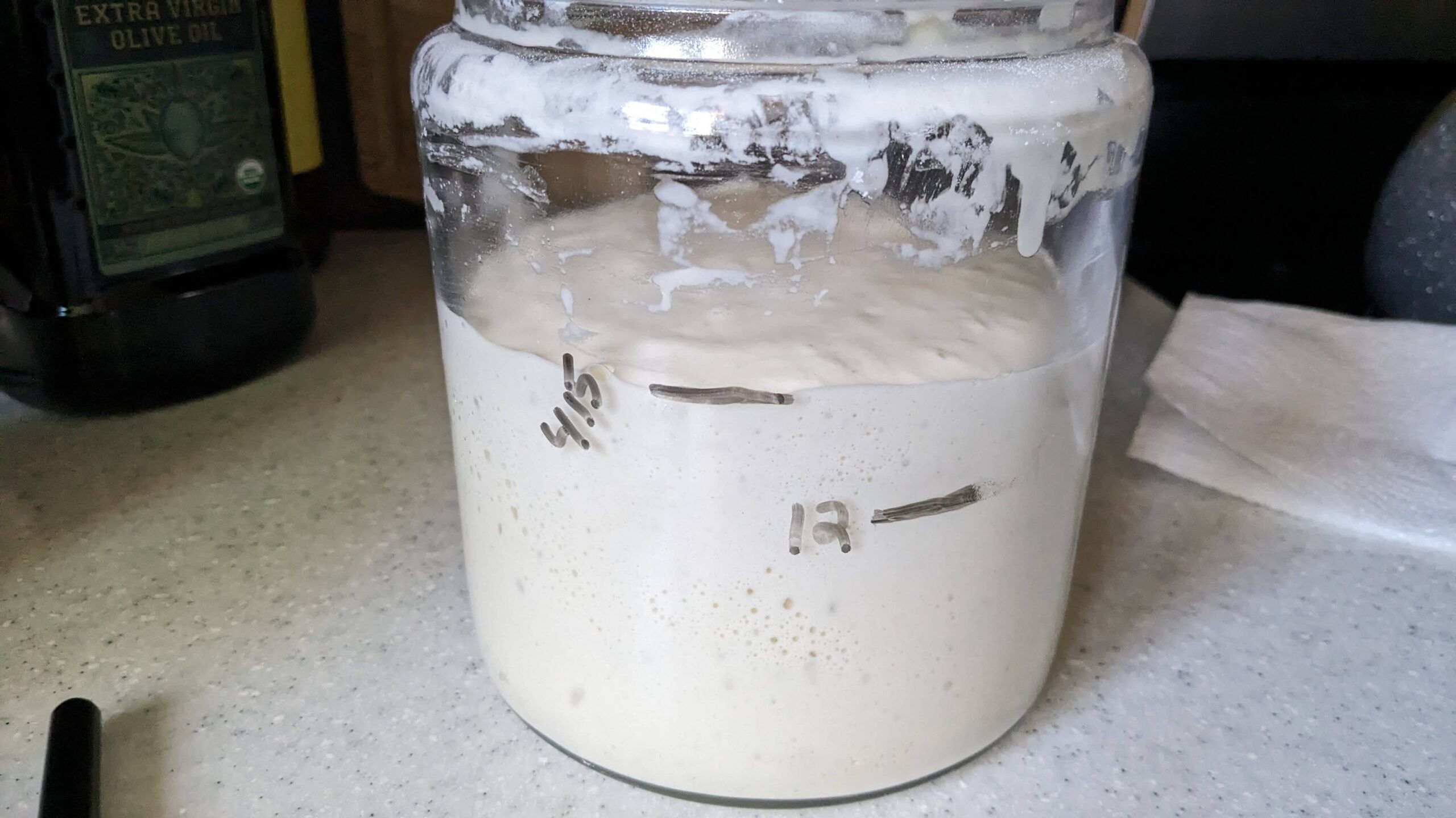 jar of rising sourdough starter on a stove top showing a span of 4 hours