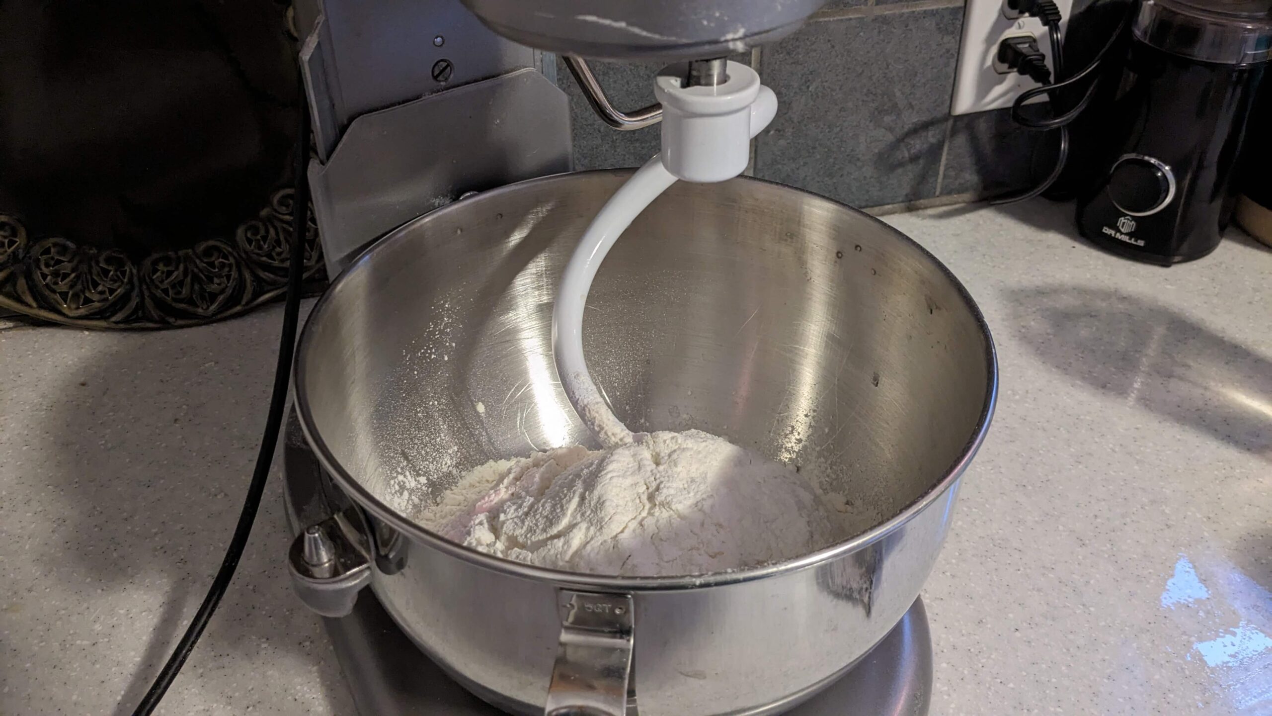 dry ingredients in the bowl of a kitchen aid mixer with a dough hook