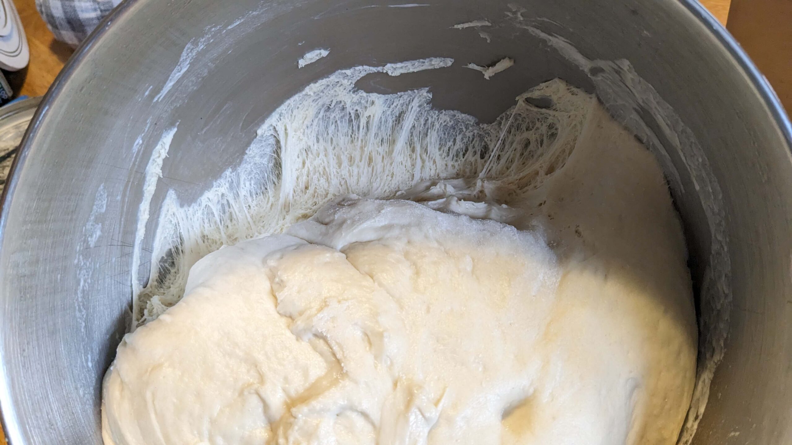 bread dough pulling away from the wall of a silver bowl