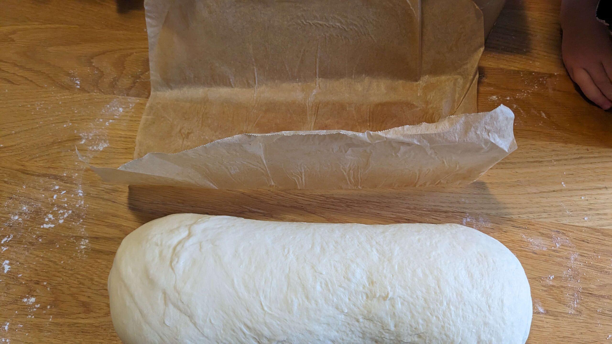 rolled sourdough bread loaf next to parchment paper