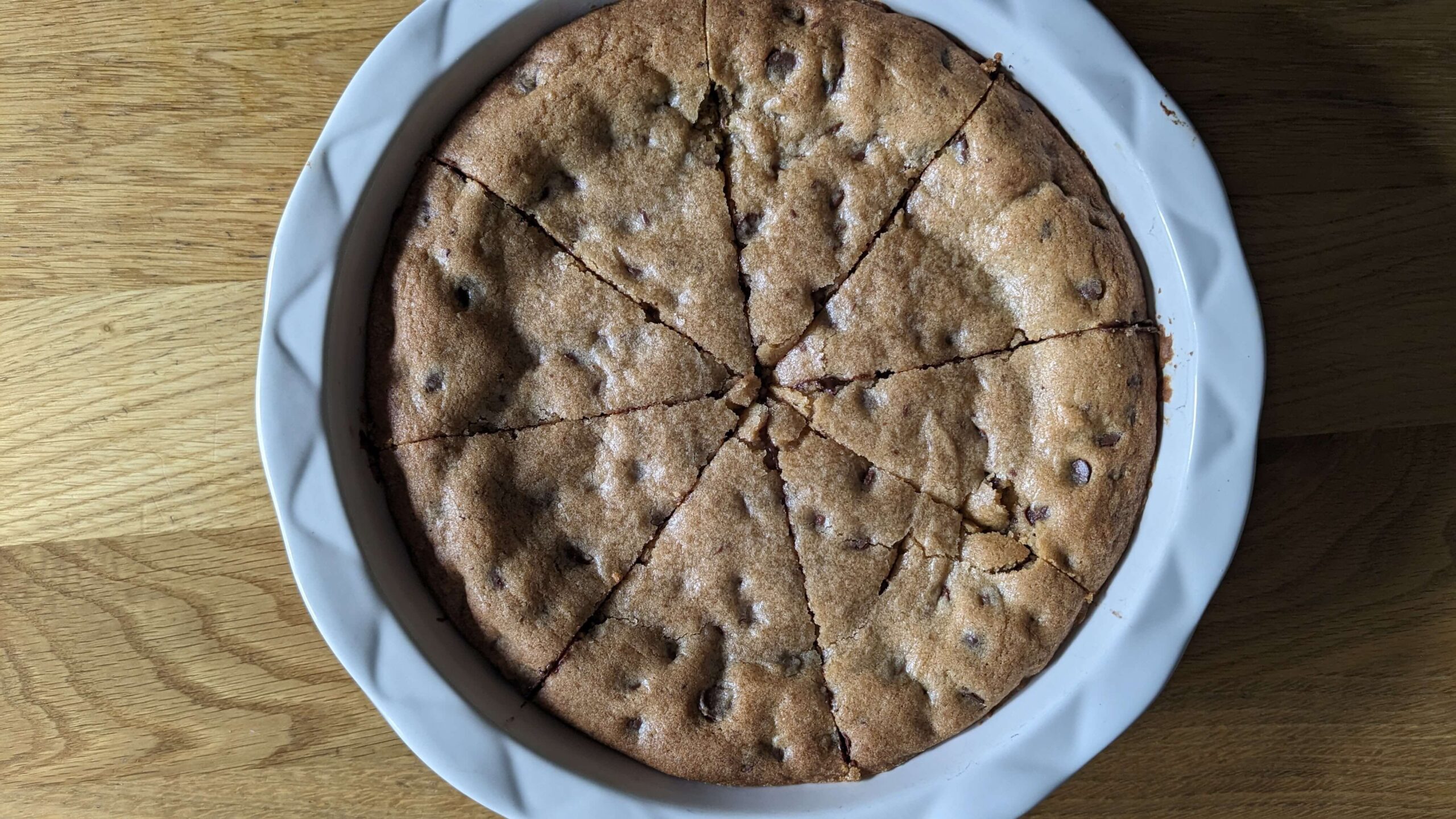 a pie plate holding chocolate chip cookie pie cut into eight slices 