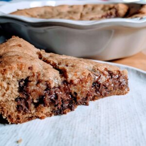 chocolate chip cookie pie sliced on a plate in front of a pie pan