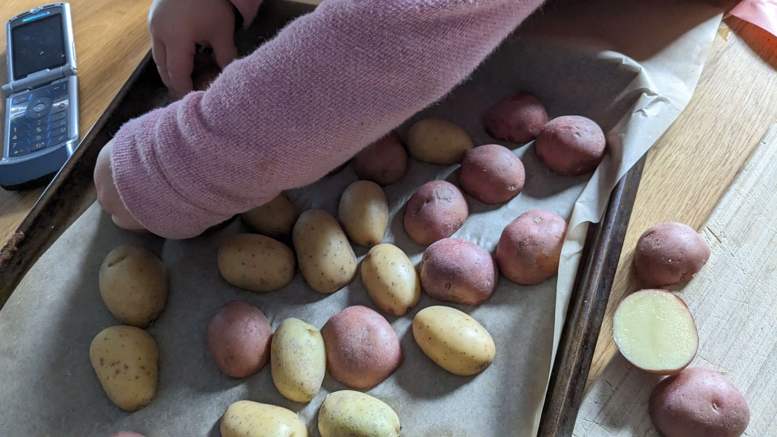 toddler flipping potato halves on a tray of lined with parchment paper