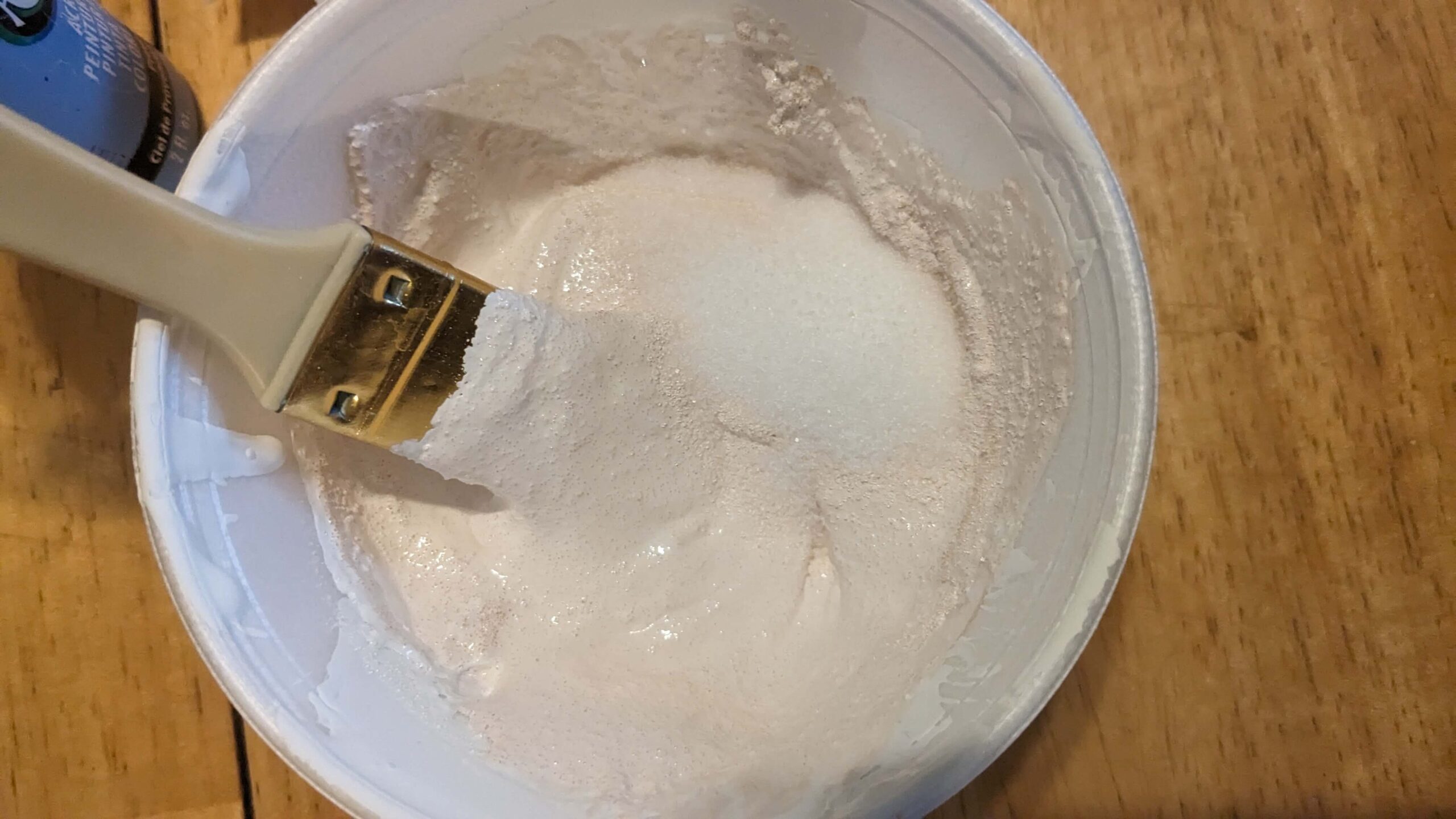 a paint brush mixing salt and tan colored paint