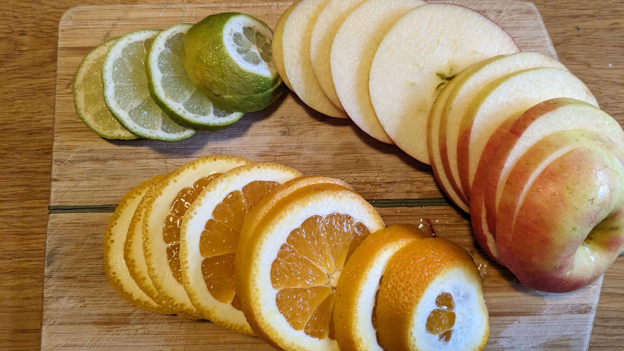 sliced lime, orange, and apple on a cutting board