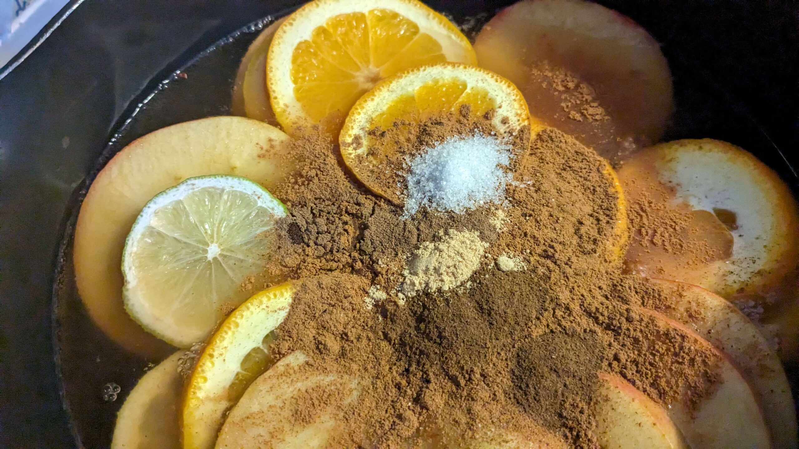 assorted spices on sliced fruit in a pot of apple juice