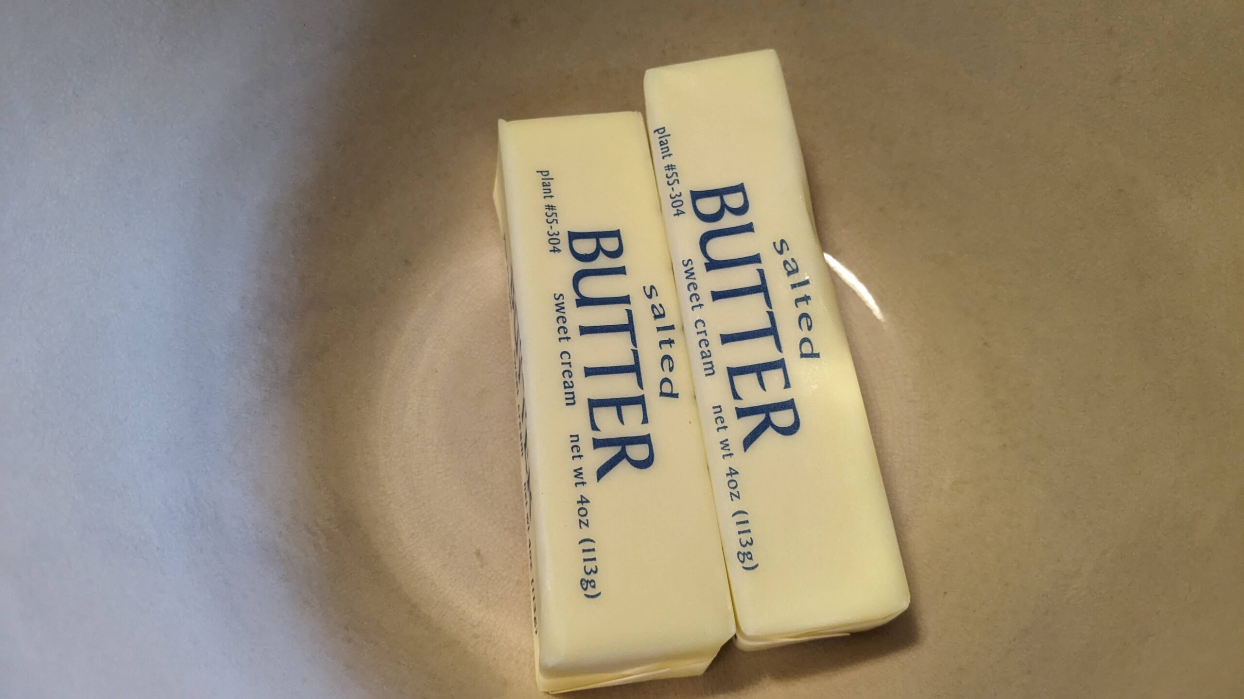 two wrapped sticks of butter in a bowl