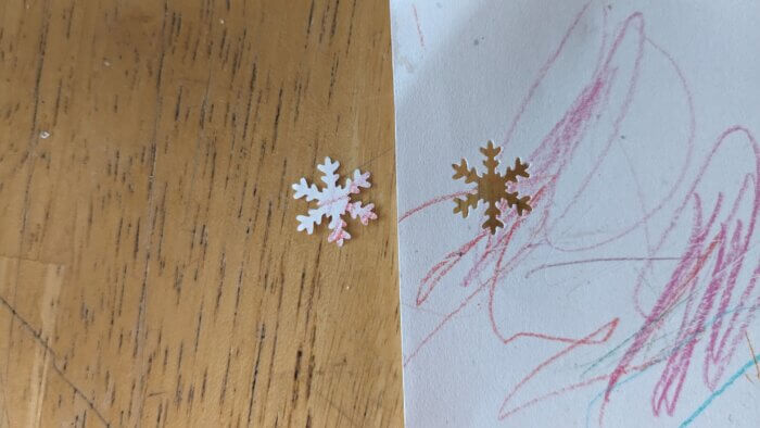 a snowflake punch out of a white paper with red scribbles