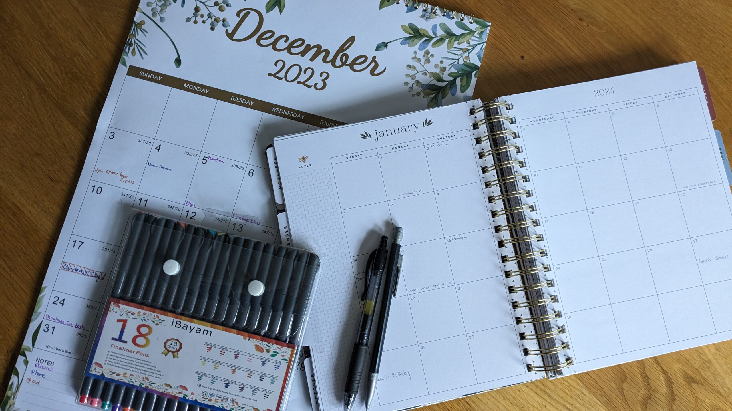 a happy planner laying on a wall calendar with pens 