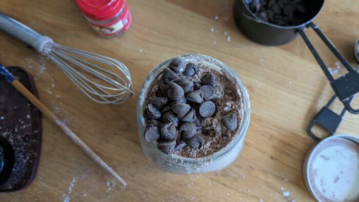 chocolate chips on top of a spiced hot chocolate mix in a mason jar
