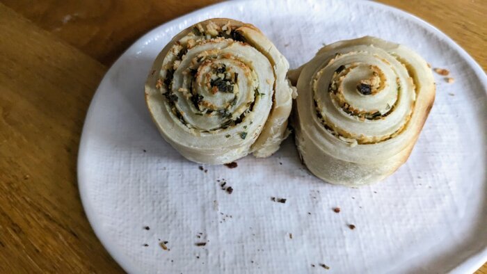 Two white cheddar and chive rolls on a white plate