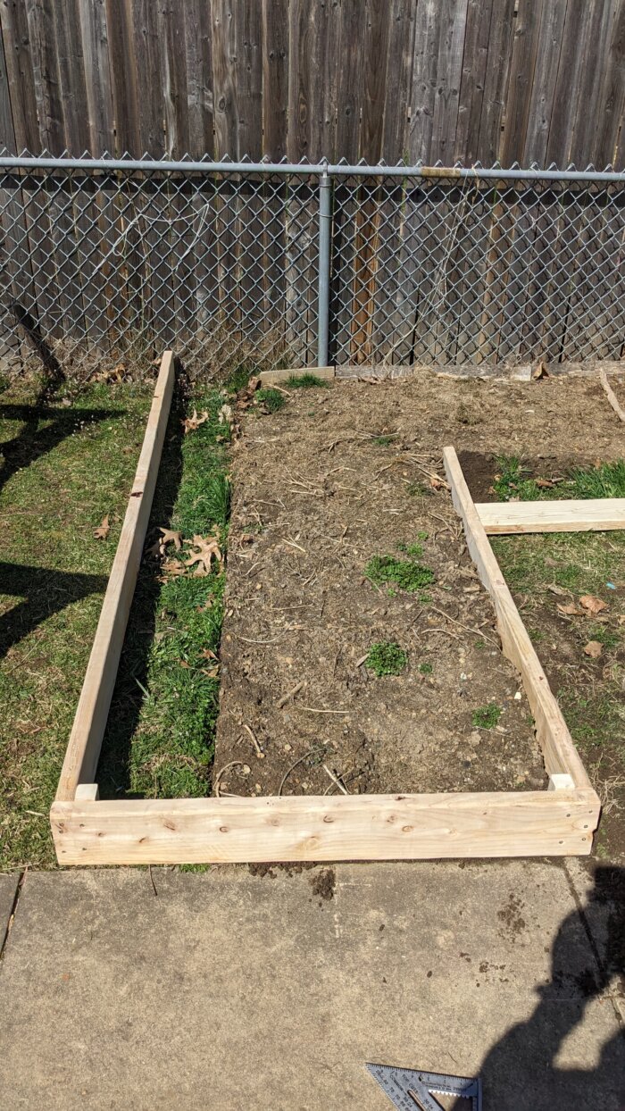 A raised bed with soil on the right side and a small patch of grass on the left.