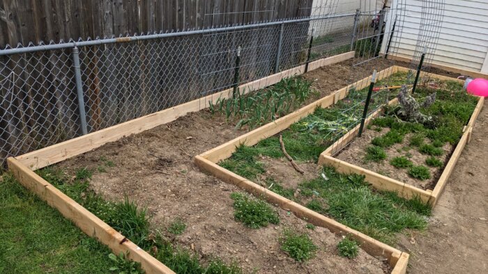 An unfilled larger raised bed in the shape of a U and smaller unfilled raised bed inside of it.