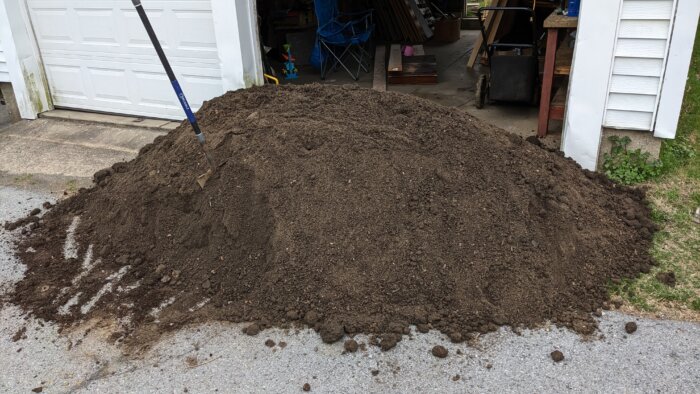 A large pile of soil in front of a garage door.