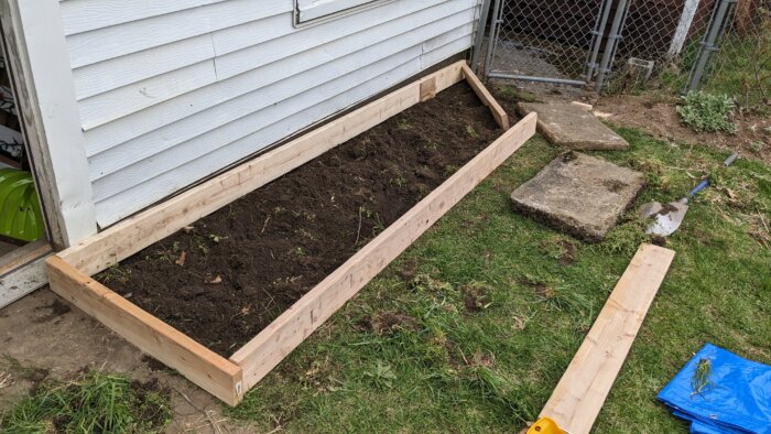 A small raised bed in front of a garage wall.