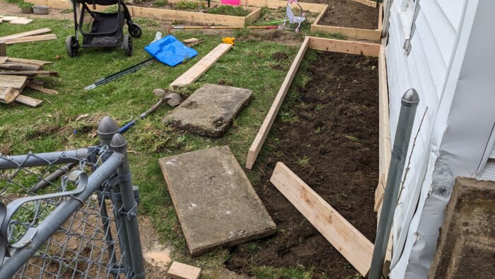 Two concerete slabs laying next to an unfinished raised bed.