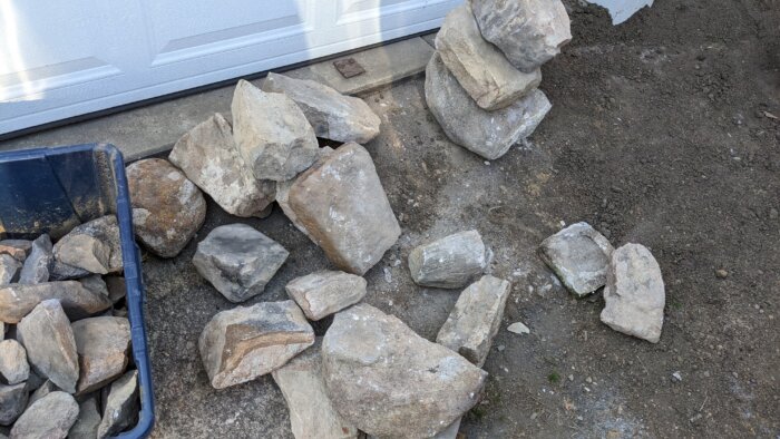 A pile of large rocks in front of a garage.