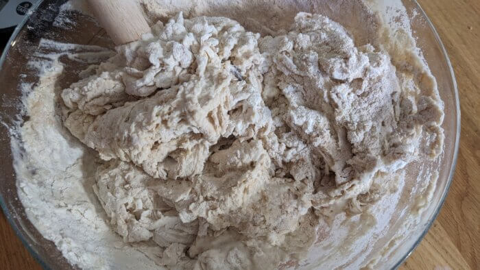 a dough mixture in a glass bowl with a danish dough whisk