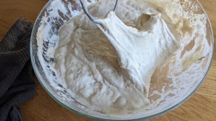 danish dough whisk pulling up sourdough dough in a glass bowl