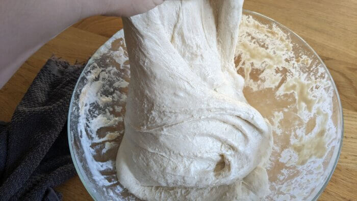 hand pulling up sourdough dough that has gone through multiple stretch and folds