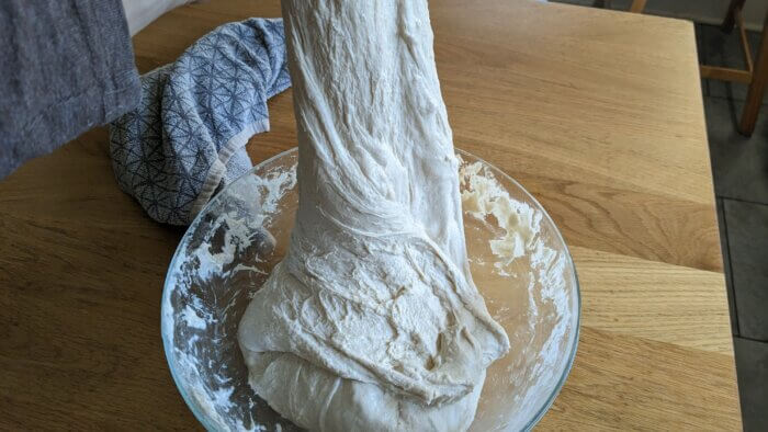 sourdough dough that is being stretched by hand