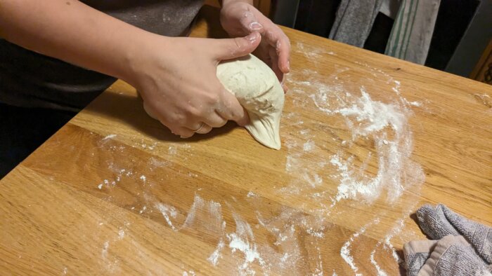 woman tucking a rolling sourdough dough into a ball