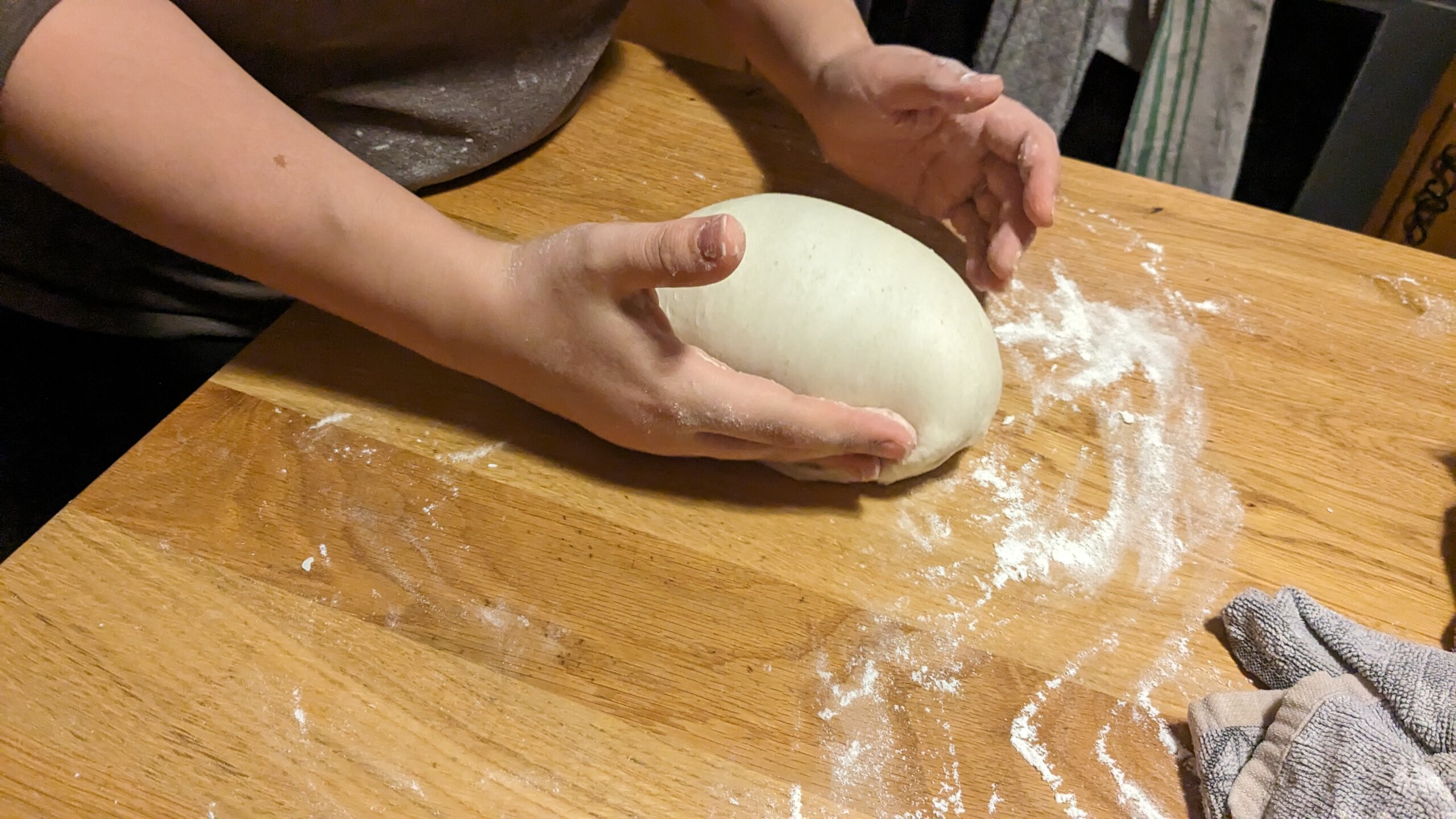 woman twisting a loaf of dough into a round loaf